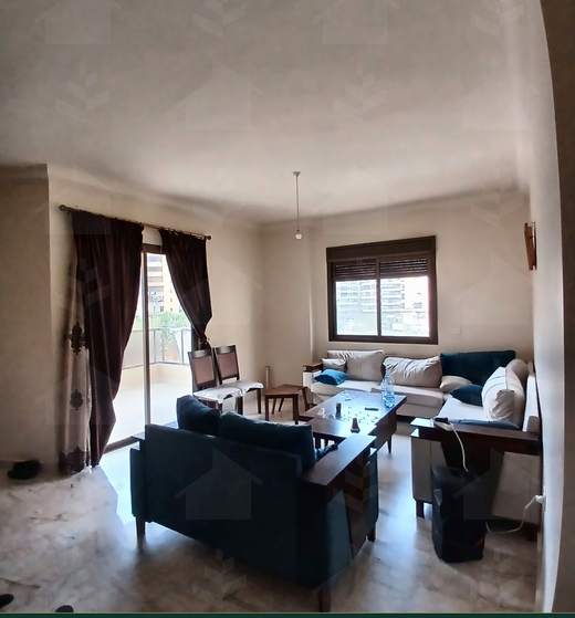 Living room from the window side, with seating and curtained full-height windows, furnished apartment for sale in Hay El Amerkan, Hadath — Ref. 1197