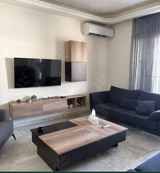 Second salon with wall-mounted television and daylight from the balcony doors, apartment for sale in Zarif, Beirut — Ref. 1195