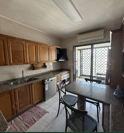 Fully equipped kitchen with granite worktops opening onto the closed balcony used as an external kitchen, apartment for sale in Zarif, Beirut — Ref. 1195
